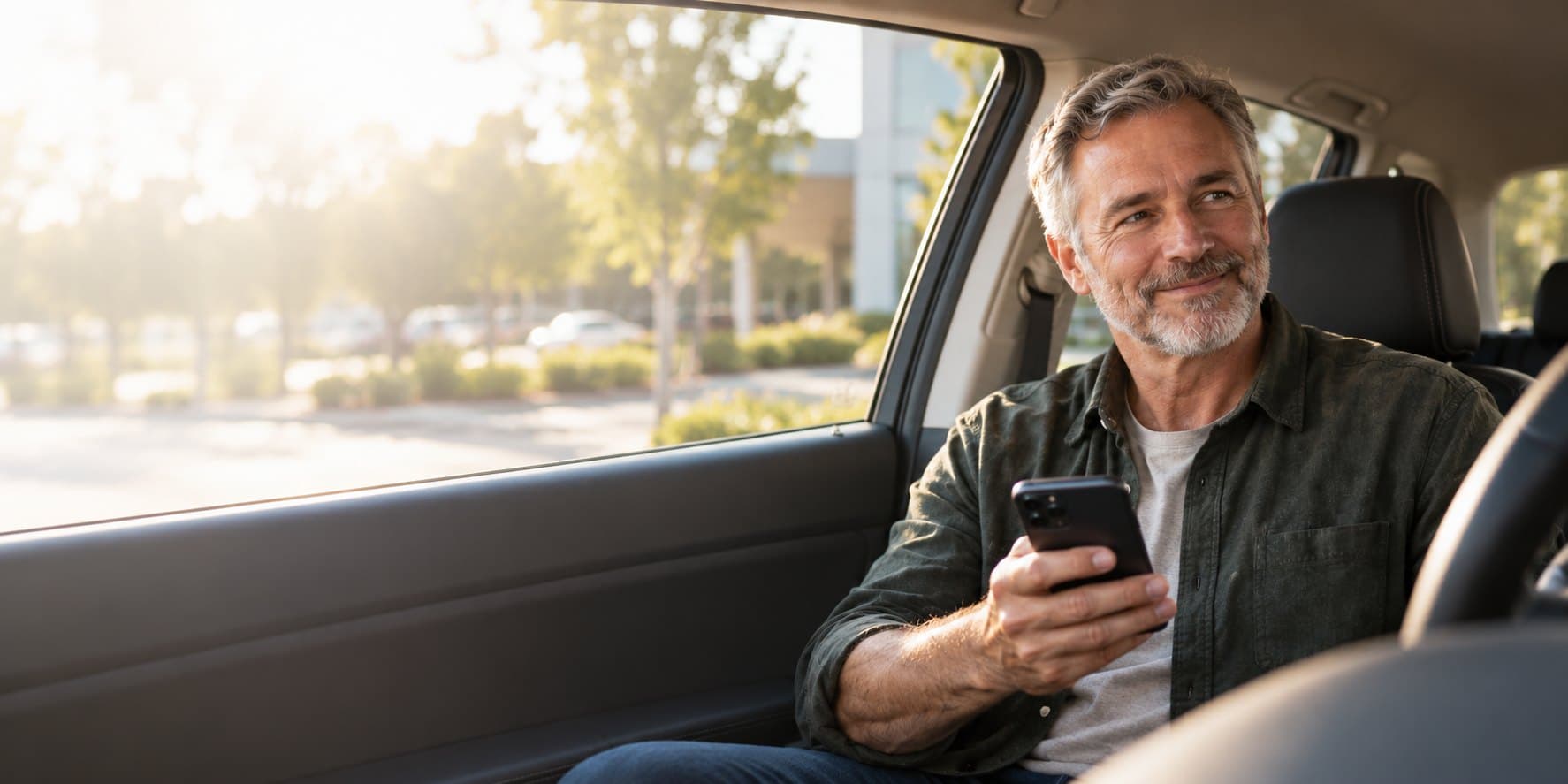 A person sits in the front seat of a parked car, holding their phone, after an appointment.